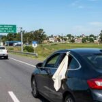 What does it mean to see a white cloth hanging from a car window on the road?